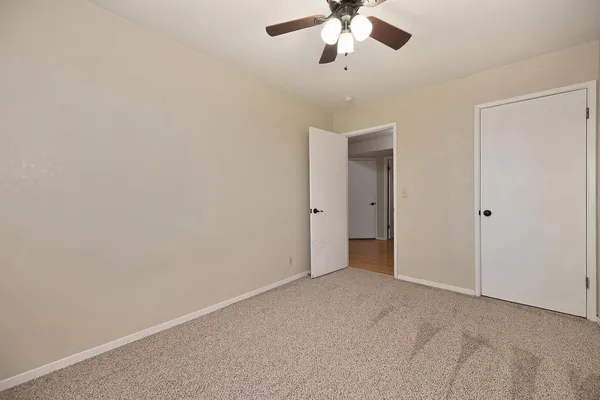 an empty room with a chandelier fan and closet