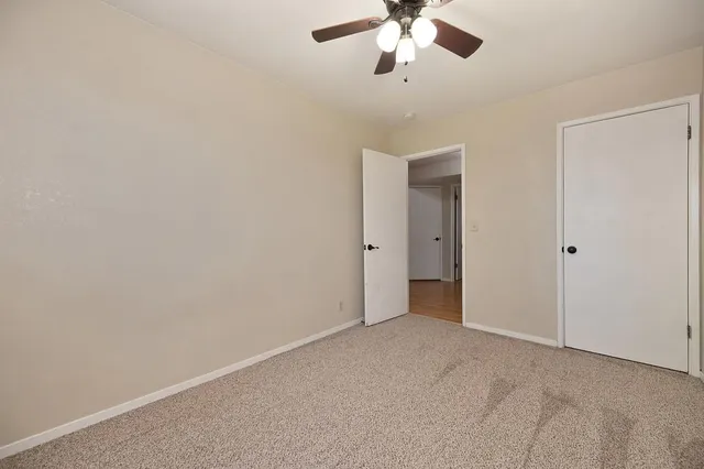 an empty room with a chandelier fan and closet