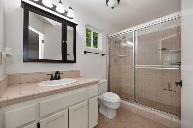 a bathroom with a toilet a sink a glass door a shower a mirror and vanity