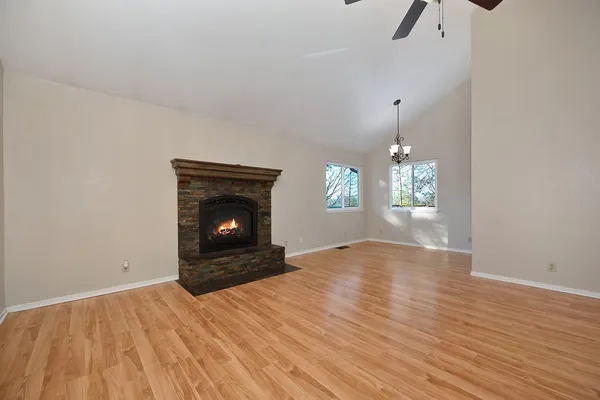 a view of an empty room with wooden floor fireplace and a window