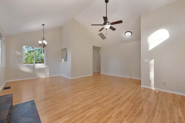 a view of empty room with wooden floor and window