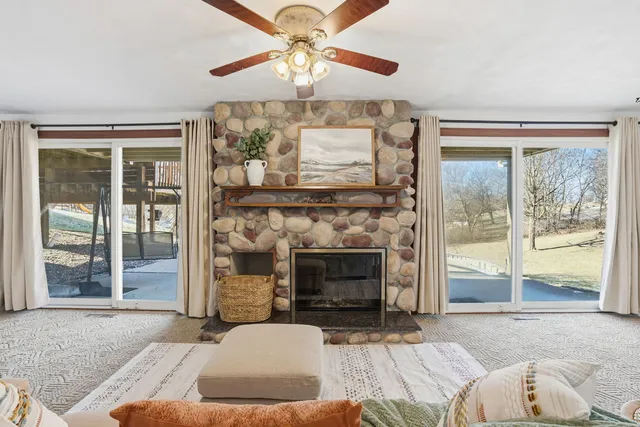 a living room with furniture a fireplace and a floor to ceiling window