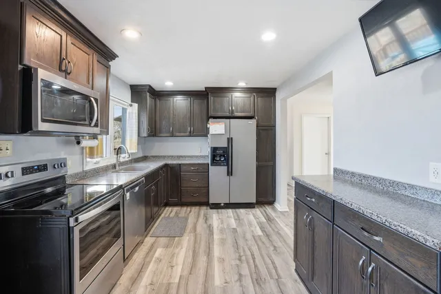 a kitchen with stainless steel appliances granite countertop a refrigerator a stove top oven a sink and dishwasher