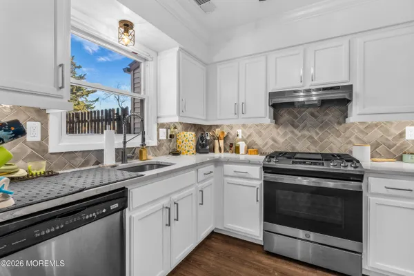 a kitchen with granite countertop white cabinets and stainless steel appliances