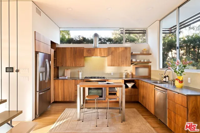 a kitchen with stainless steel appliances a table and chairs in it