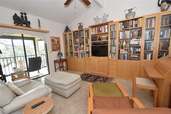 a living room with furniture a bookshelf and a flat screen tv