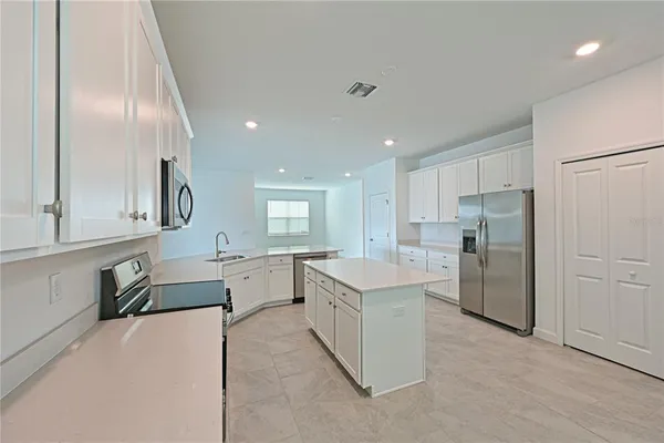 a large kitchen with a refrigerator a sink dishwasher with a dining table and chairs