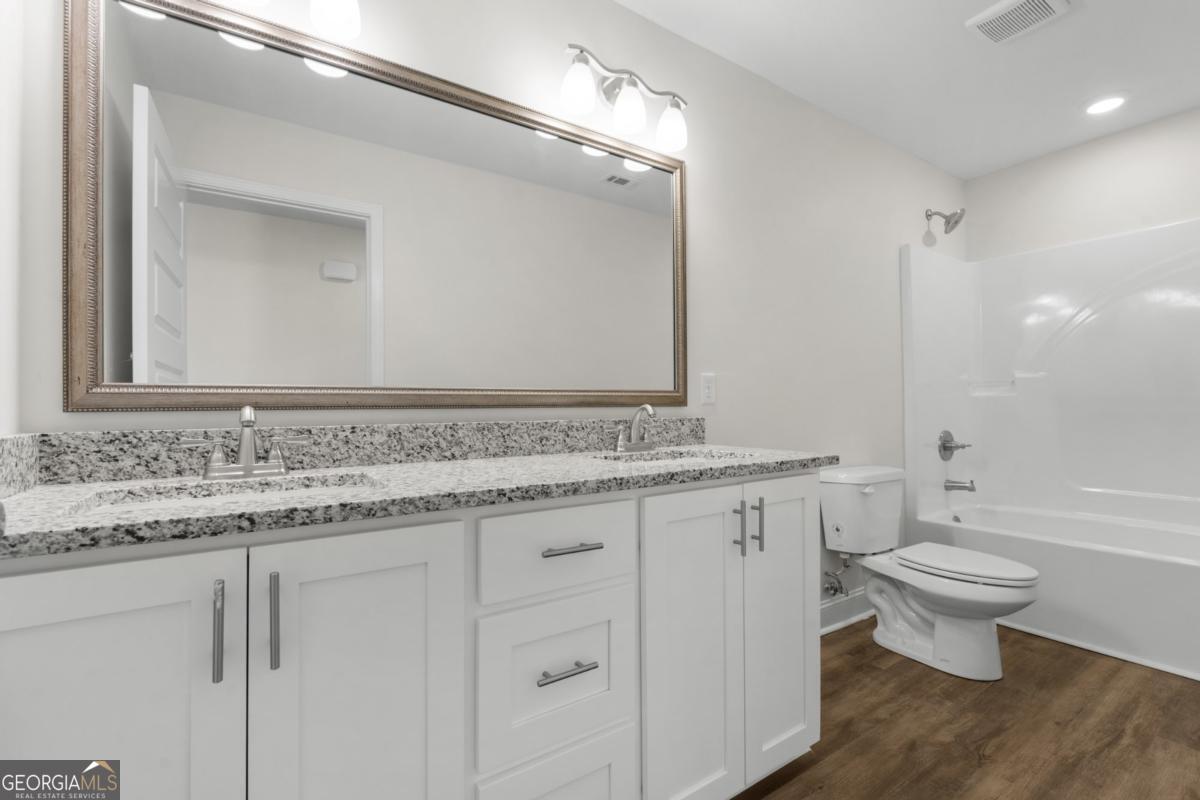 909 Ryegrass Road, Unit 81 Statesboro, GA 30458 - Photo 14 of 23 a bathroom with a granite countertop sink a toilet and a mirror