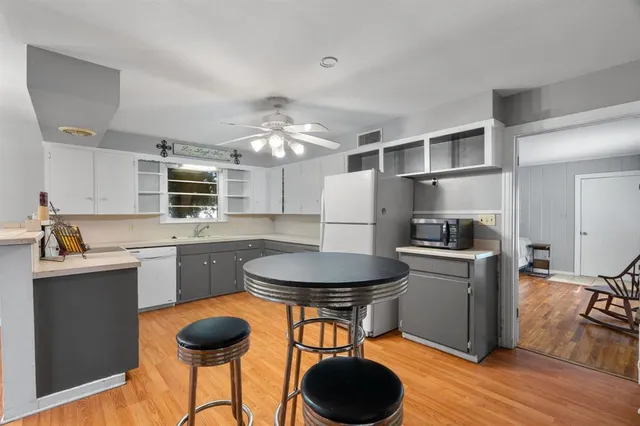 a kitchen with stainless steel appliances a dining table chairs stove refrigerator and cabinets