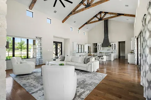 a living room with couches and kitchen view with wooden floor