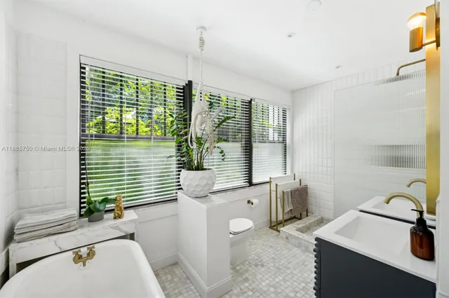 a bathroom with a sink a bathtub and next to a window