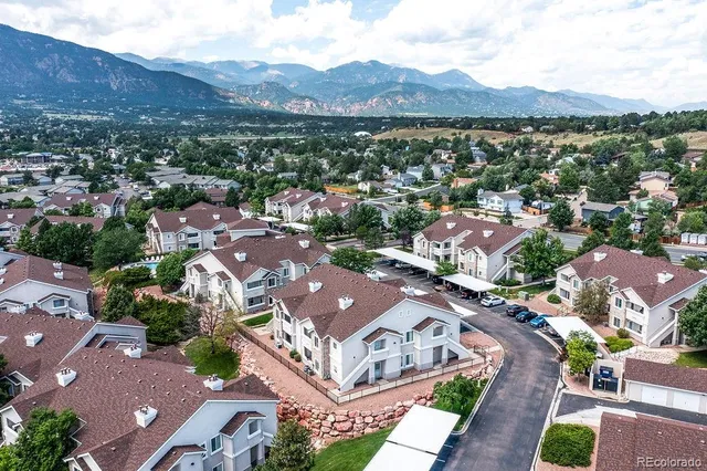 an aerial view of a city with lots of residential buildings and mountain view in back
