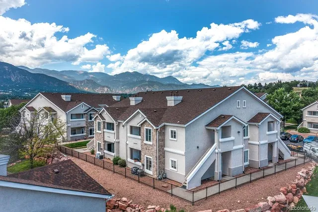 a view of a white house next to a yard with large trees