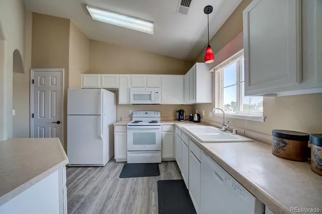 a kitchen with a sink dishwasher a refrigerator a stove and white cabinets with wooden floor