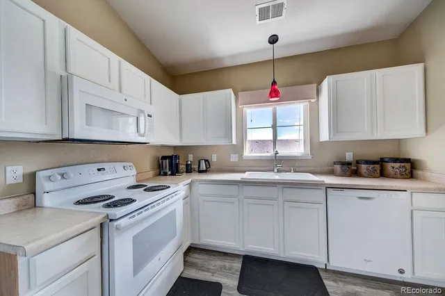 a kitchen that has a lot of white cabinets and a window