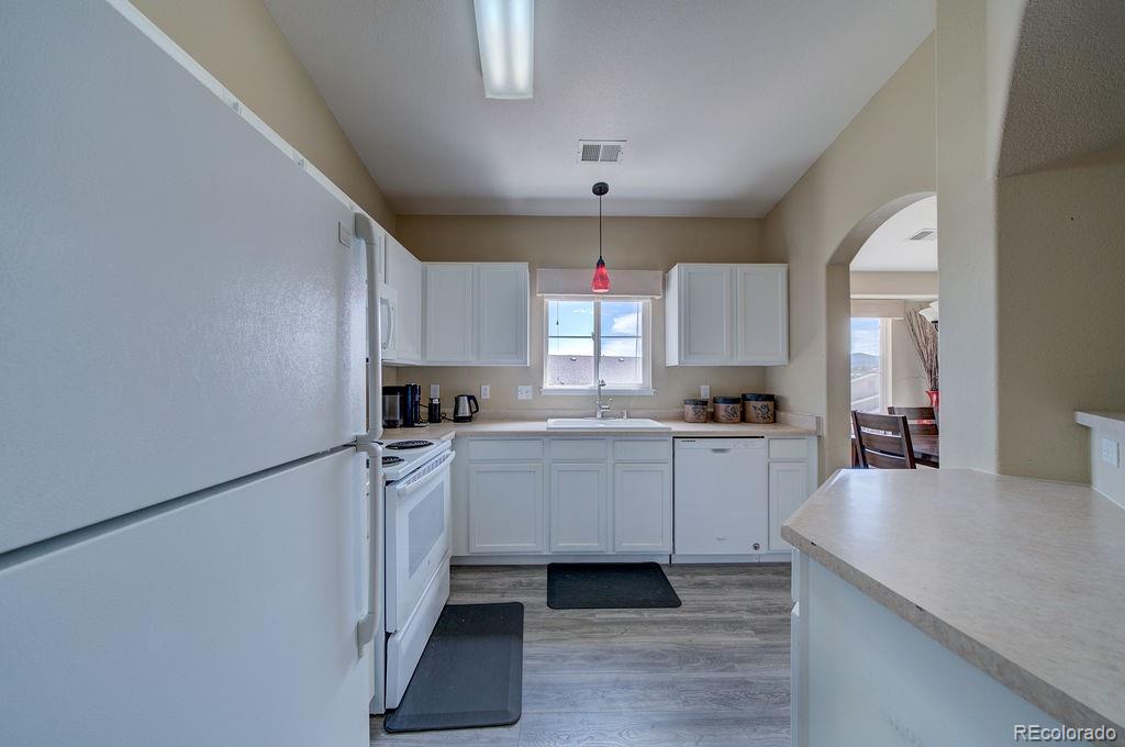 3875 Strawberry Field Grove Colorado Springs, CO 80906 - Photo 35 of 50 a kitchen with white cabinets and white appliances