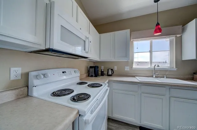 a kitchen with a sink a stove and white cabinets