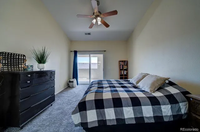 a spacious bedroom with a bed a chandelier and a potted plant on a dresser