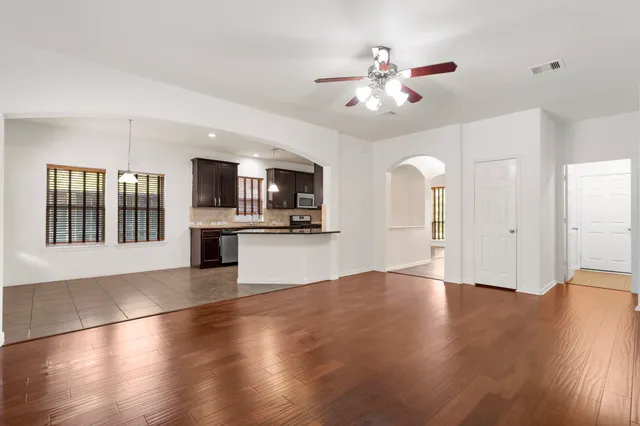 a view of an empty room with kitchen and window
