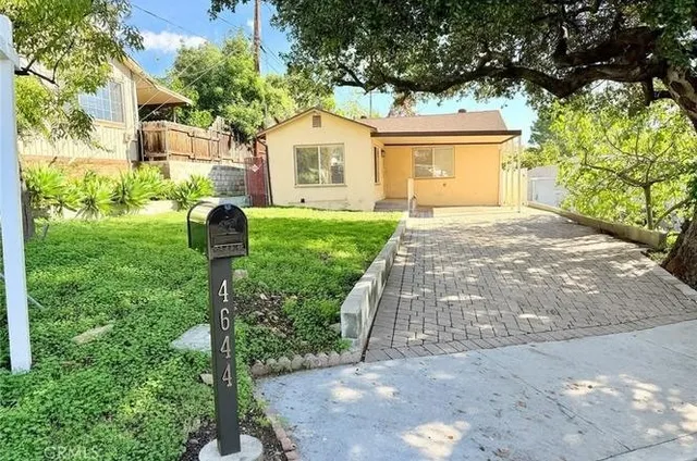 a front view of a house with a yard and trees