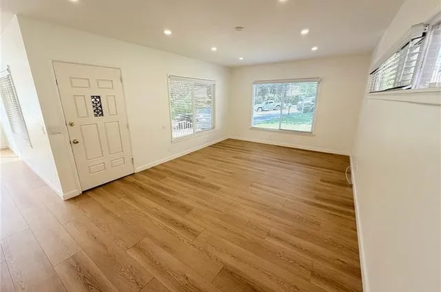 a view of an empty room with wooden floor and a window