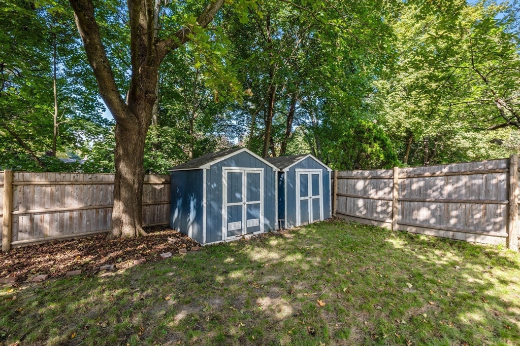 92 Old Connecticut Path Framingham, MA 01701 - Photo 23 of 24 a view of a small yard with large trees and wooden fence