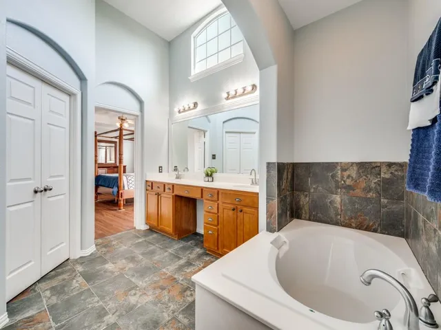 a bathroom with a tub sink and mirror