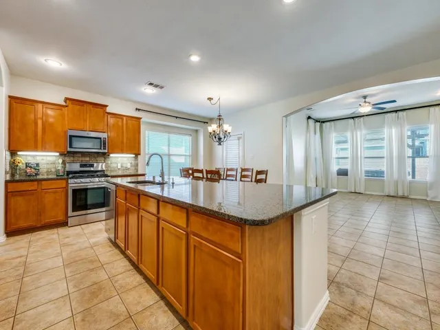 a kitchen with stainless steel appliances granite countertop a refrigerator a stove top oven and white cabinets
