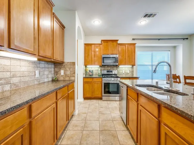 a kitchen with stainless steel appliances granite countertop a sink counter space cabinets and a large window