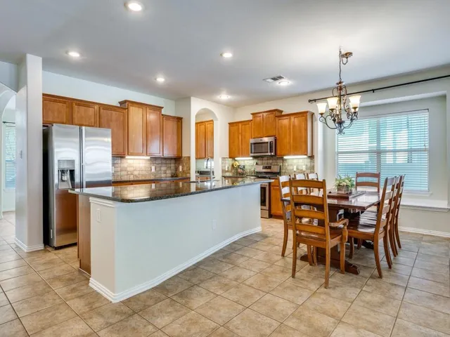 a kitchen with stainless steel appliances granite countertop a table and chairs in it
