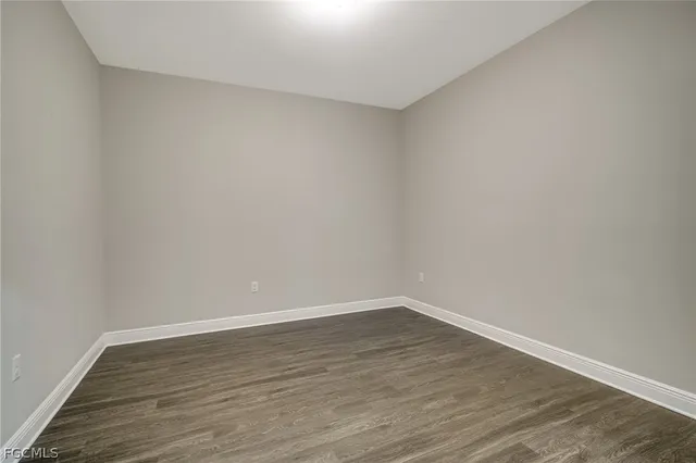 a view of an empty room with wooden floor and closet