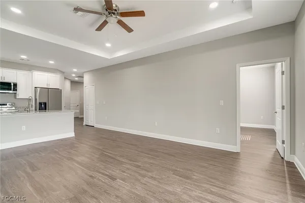 an empty room with wooden floor fan and windows
