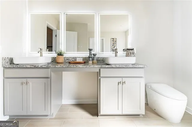 a bathroom with a granite countertop sink and a toilet