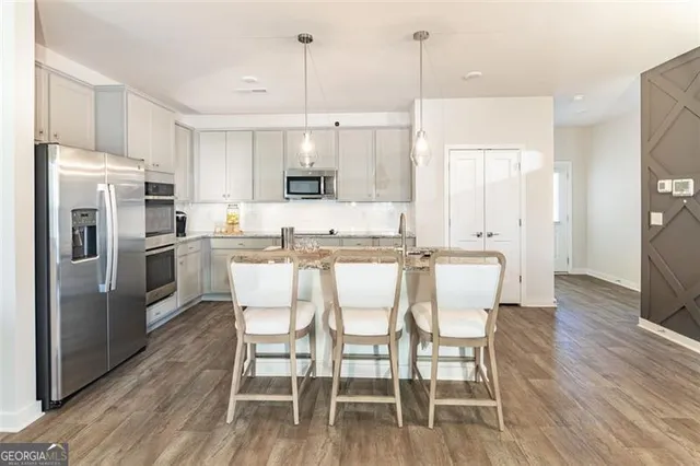 a kitchen with stainless steel appliances a dining table chairs refrigerator and sink