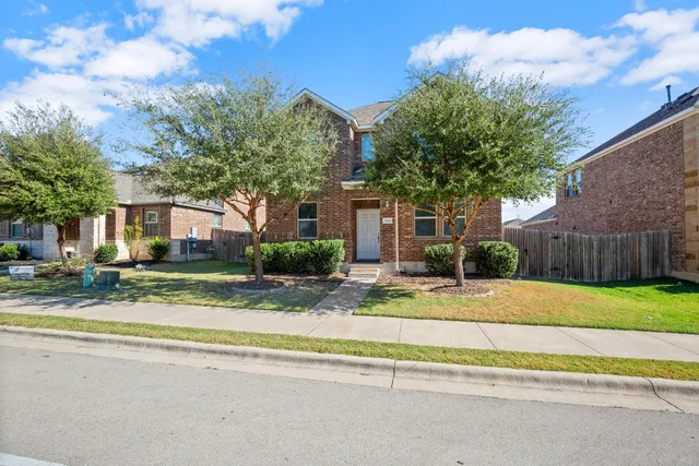 a view of white house with a yard and large tree and wooden fence