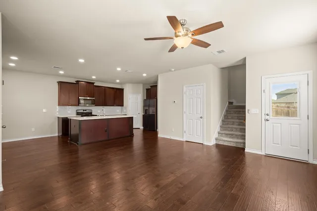 an open kitchen with kitchen island white cabinets and wooden floor