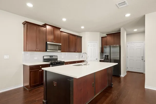 a large kitchen with stainless steel appliances refrigerator a stove top oven with wooden floors