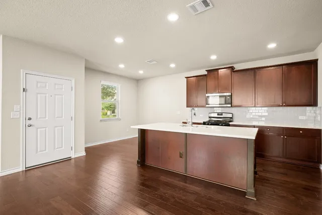 a large kitchen with stainless steel appliances a large counter top a stove and a refrigerator