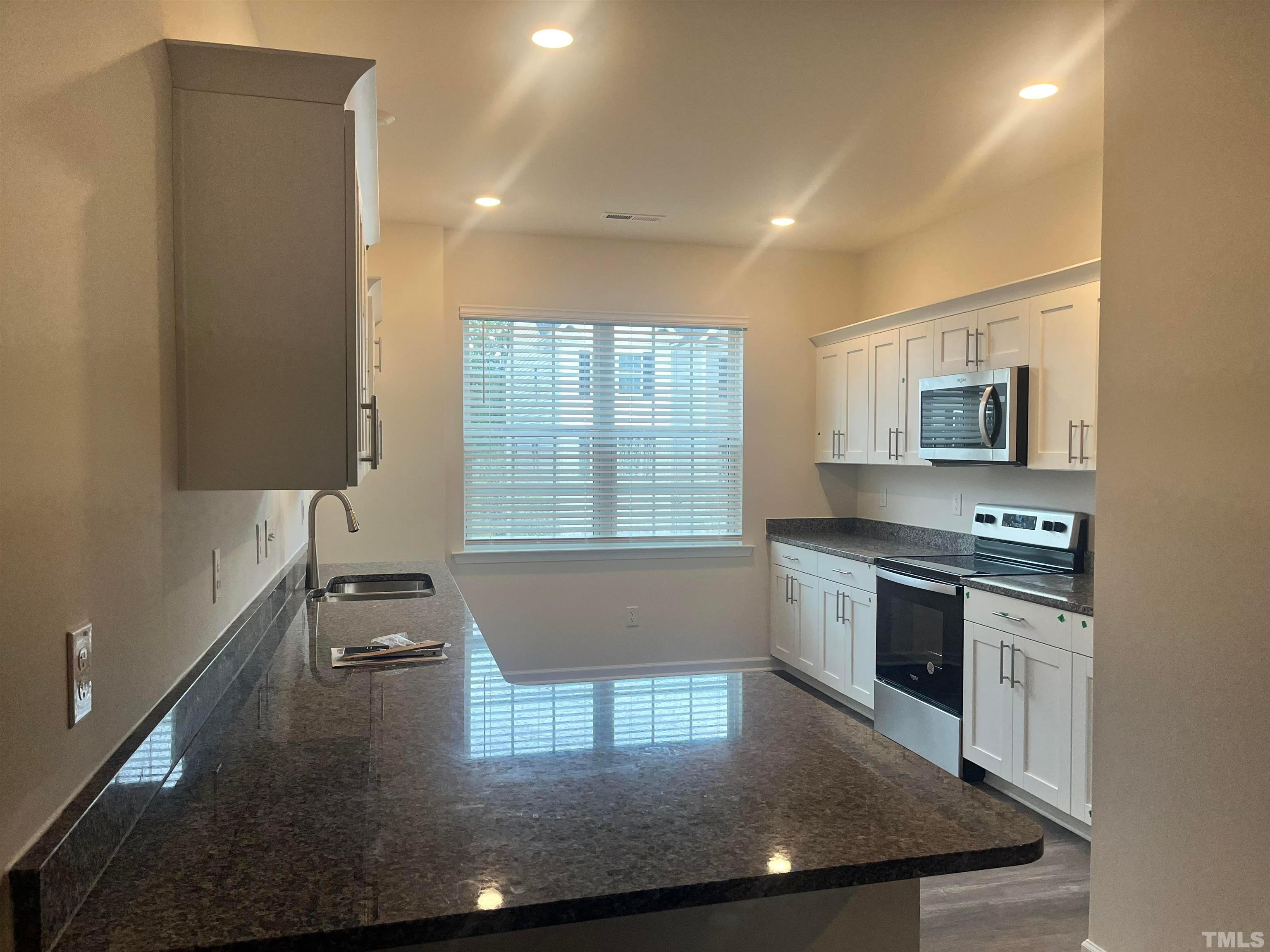 5018 Jayden Drive Durham, NC 27704 - Photo 11 of 22 a kitchen with stainless steel appliances granite countertop a sink a stove top oven a counter space and cabinets