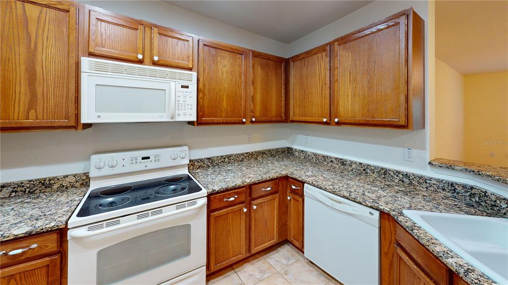 4600 East Moody Boulevard, Unit 5N Bunnell, FL 32110 - Photo 6 of 44 a kitchen with granite countertop cabinets washer and dryer