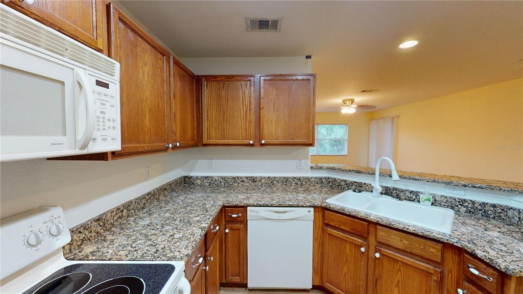 4600 East Moody Boulevard, Unit 5N Bunnell, FL 32110 - Photo 7 of 44 a kitchen with granite countertop cabinets stainless steel appliances and a counter space