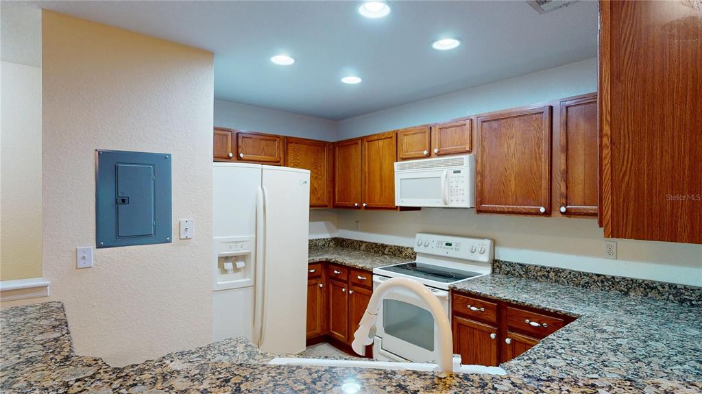 4600 East Moody Boulevard, Unit 5N Bunnell, FL 32110 - Photo 8 of 44 a kitchen with stainless steel appliances granite countertop a refrigerator a stove and a sink with wooden cabinets