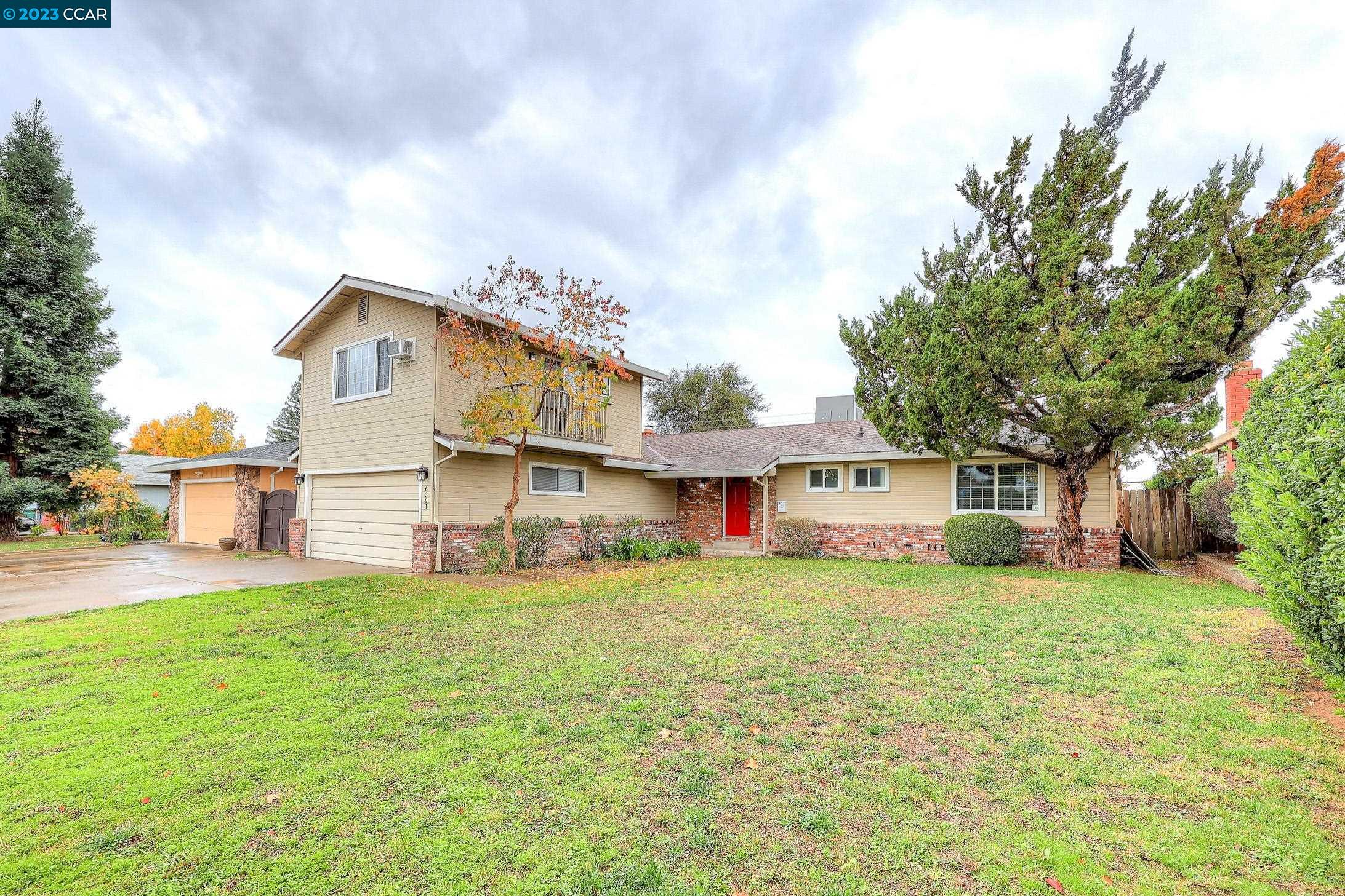 a view of a house with a big yard and large trees