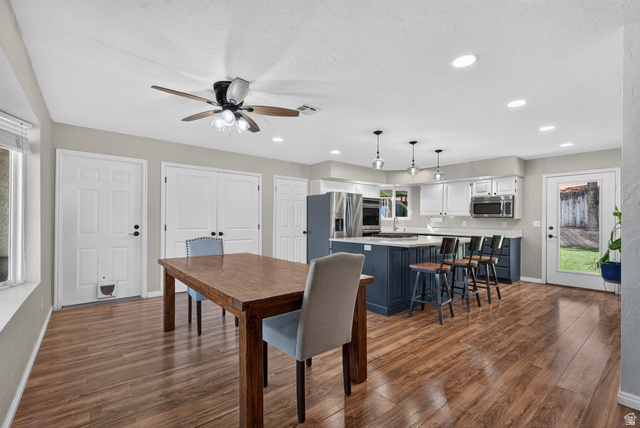 1690 Maplewood Way St. George, UT 84790 - Photo 6 of 17 Open-concept kitchen and dining area featuring hardwood flooring, stainless steel appliances, white cabinetry with dark blue island, recessed and pendant lighting, ceiling fan, and direct access to exterior spaces through French doors