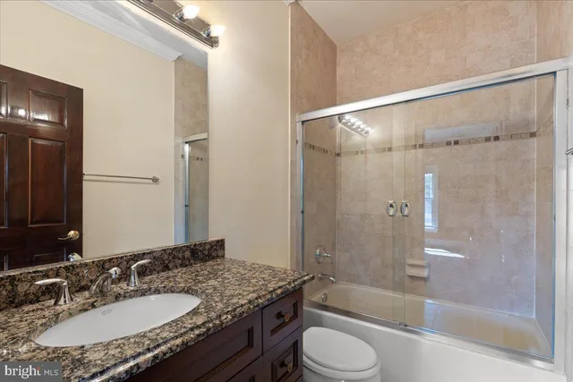 a bathroom with a granite countertop sink toilet and shower