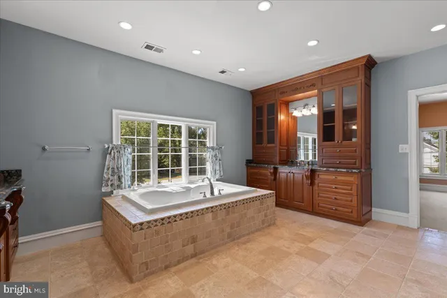 a spacious bathroom with a tub sink and mirror