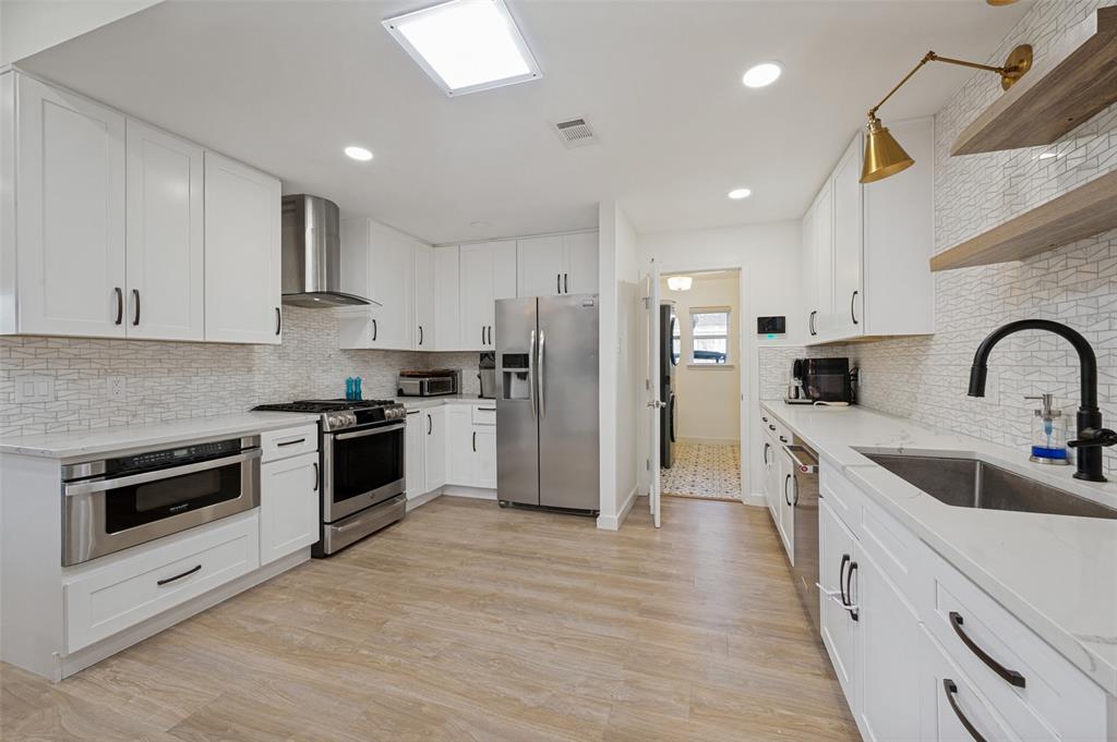 3619 Merrell Road Dallas, TX 75229 - Photo 8 of 26 Kitchen featuring extensive white cabinetry with dark hardware, quartz countertops, and a full tile backsplash