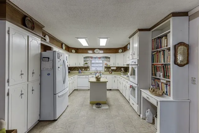 a kitchen with stainless steel appliances a sink a stove a refrigerator cabinets and dining table