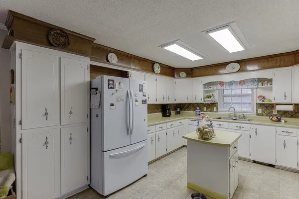 a kitchen with stainless steel appliances a sink a stove a refrigerator cabinets and dining table