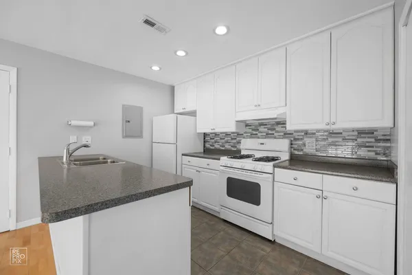a kitchen with granite countertop white cabinets and white appliances